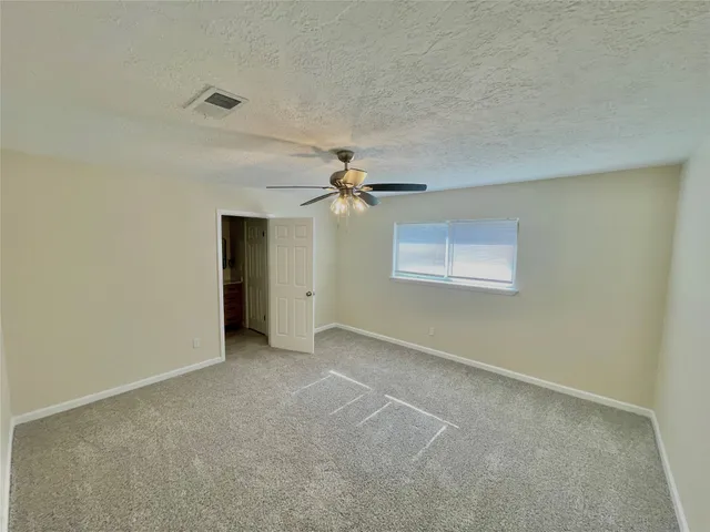 an empty room with a ceiling fan and a window