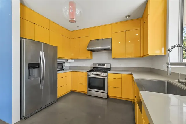 a kitchen with stainless steel appliances granite countertop a sink a stove and refrigerator