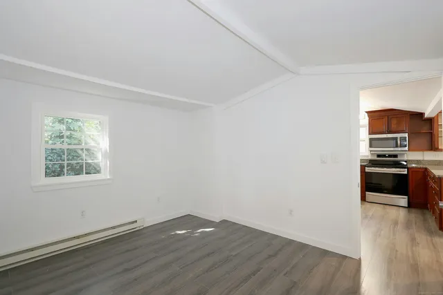 a view of a kitchen from a hallway with wooden floor and a kitchen