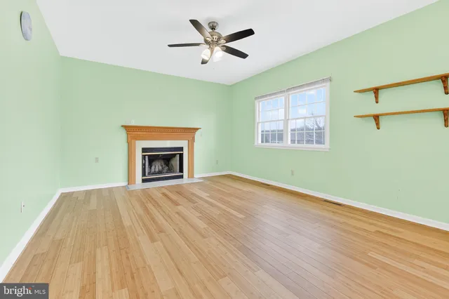 a view of an empty room with a window and a fireplace
