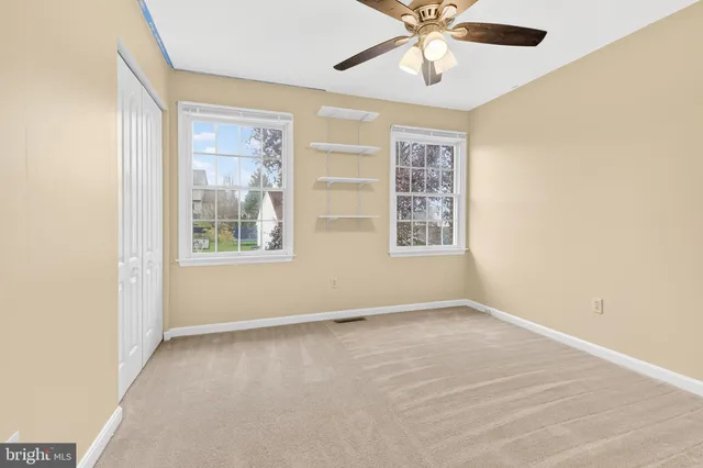 an empty room with windows and fan