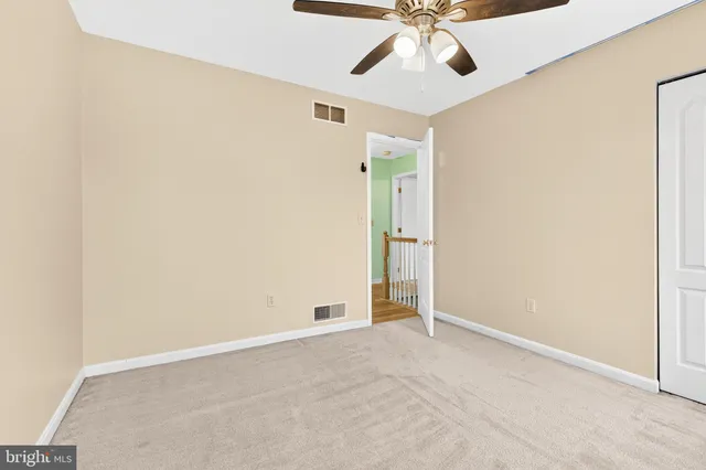 an empty room with a ceiling fan and carpet