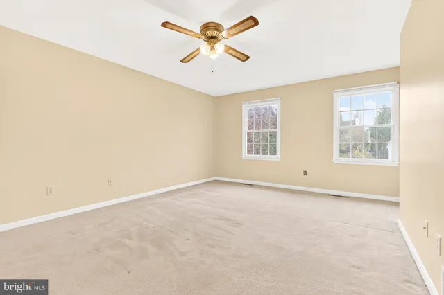 an empty room with windows and ceiling fan