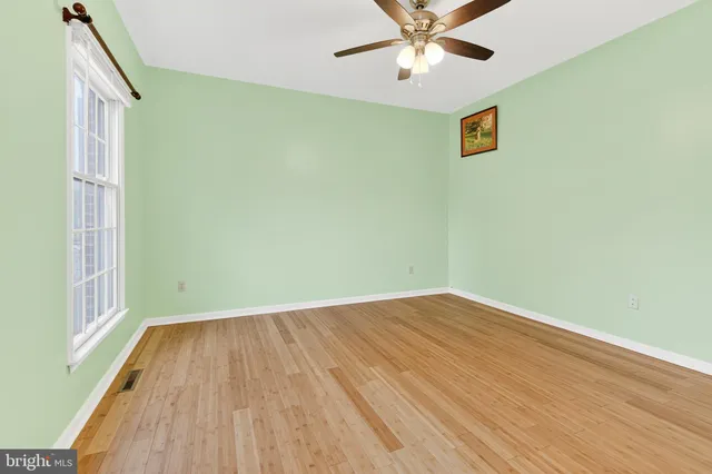 an empty room with wooden floor fan and windows