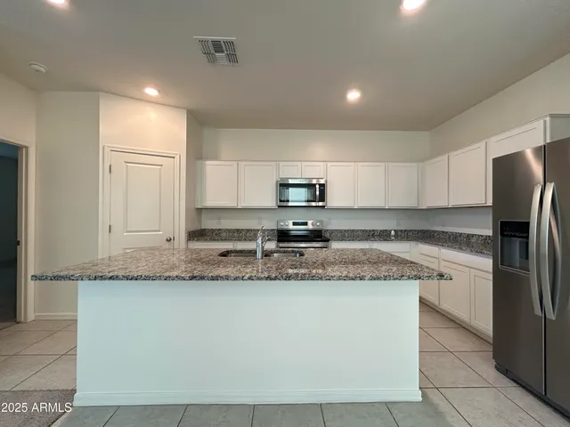 a kitchen with stainless steel appliances granite countertop a sink a stove a refrigerator and a granite counter tops