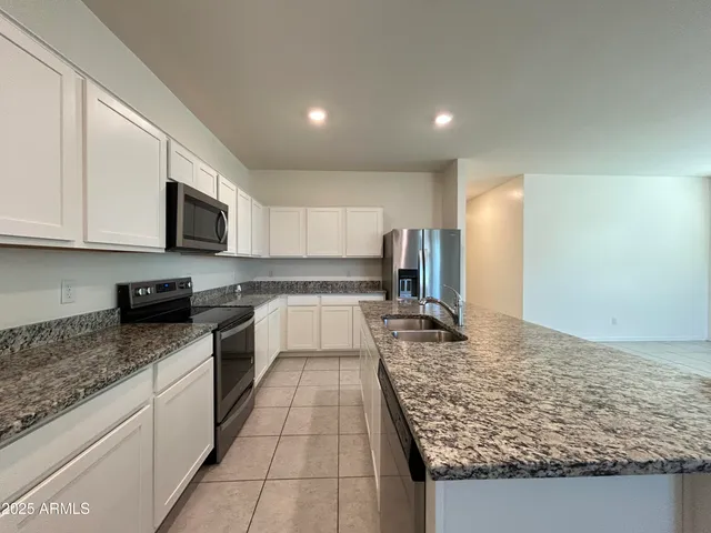 a large kitchen with stainless steel appliances granite countertop a sink stove and refrigerator