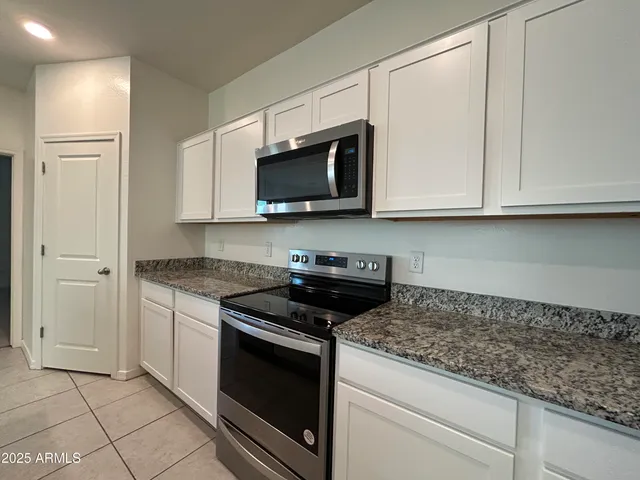 a kitchen with granite countertop white cabinets stainless steel appliances and a sink