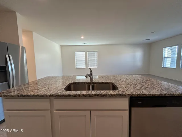 a kitchen with kitchen island granite countertop a sink and refrigerator