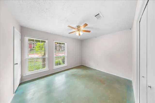 a view of an empty room with chandelier fan and a window