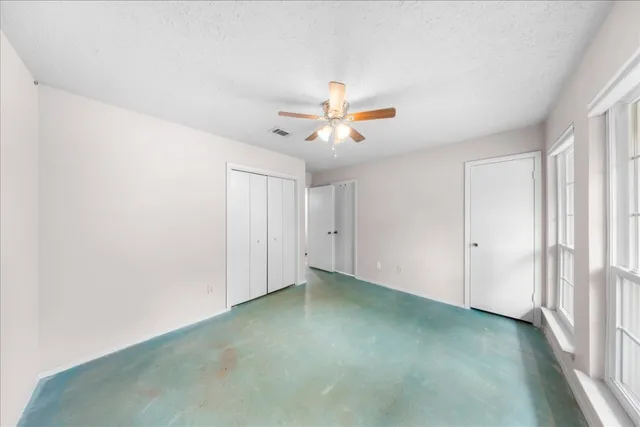an empty room with closet and a ceiling fan