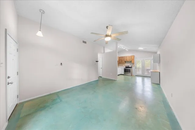 an empty room with ceiling fan and window
