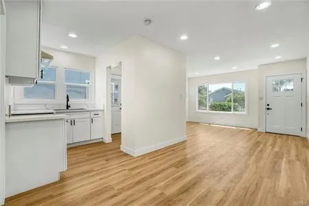 a kitchen with white cabinets and wooden floor