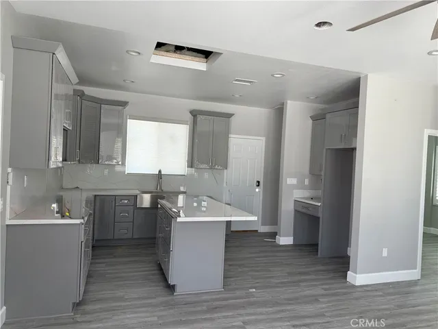 a large room with stainless steel appliances kitchen island granite countertop a sink and wooden floors