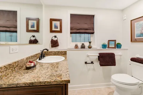 a bathroom with a granite countertop sink mirror vanity and toilet