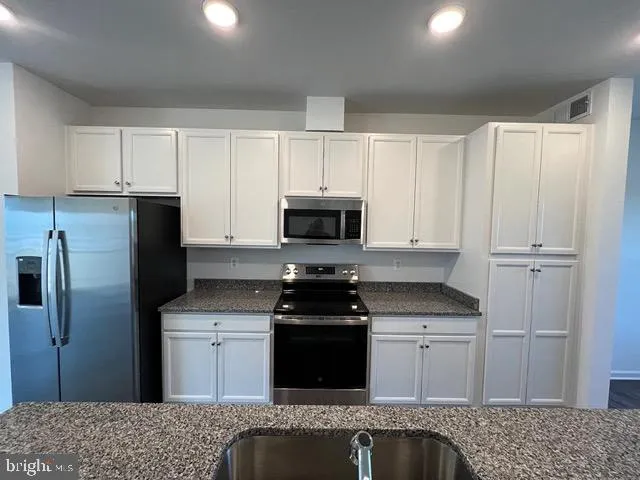 a kitchen with granite countertop white cabinets and stainless steel appliances