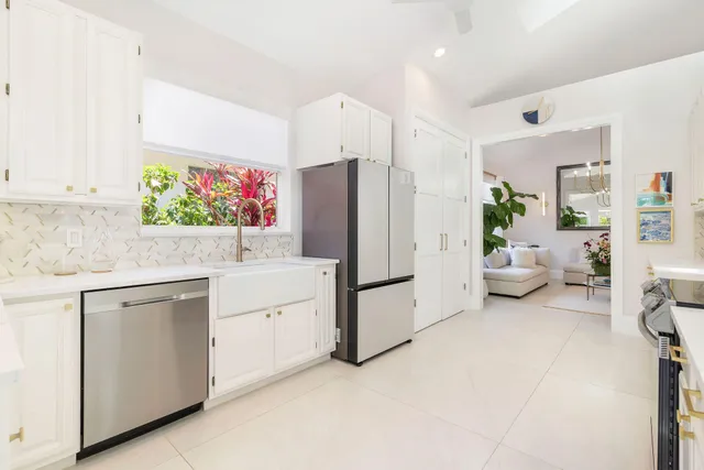 a kitchen with stainless steel appliances granite countertop a stove top oven a sink dishwasher and white cabinets with wooden floor