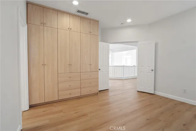 an empty room with wooden floor cabinet and windows