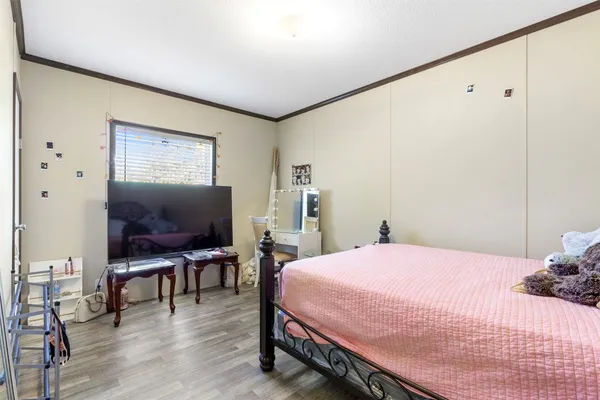 a bedroom with a bed table chair and a flat screen tv