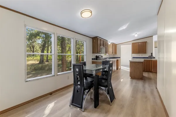 a kitchen with stainless steel appliances granite countertop a refrigerator a stove a sink a dining table and chairs with wooden floor