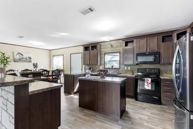 a kitchen with stainless steel appliances granite countertop sink stove top oven and refrigerator