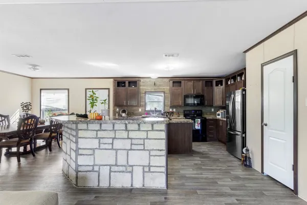 a kitchen with stainless steel appliances kitchen island granite countertop a stove refrigerator and cabinets