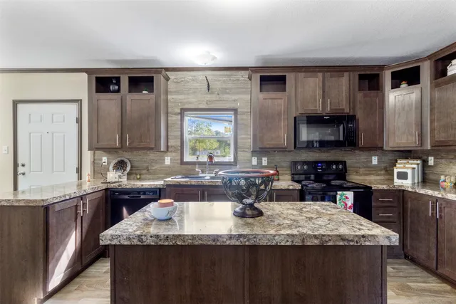 a kitchen with kitchen island granite countertop a sink counter top space appliances and cabinets