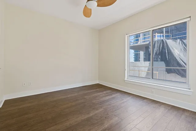 a view of an empty room with a window and wooden floor