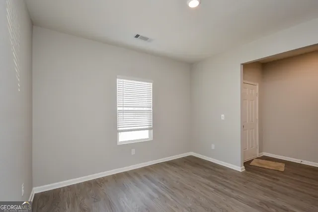 a view of an empty room with wooden floor and closet