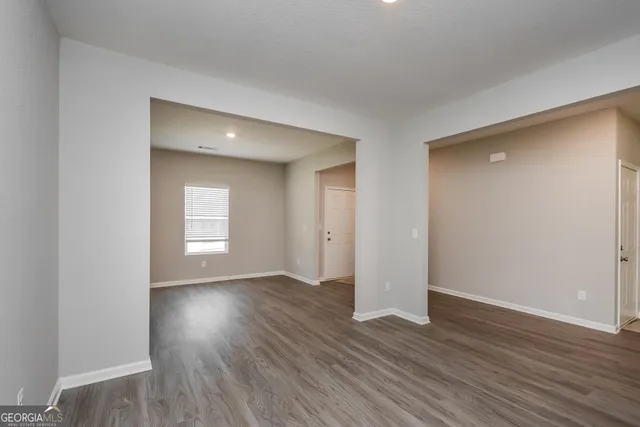 a view of an empty room with window and wooden floor