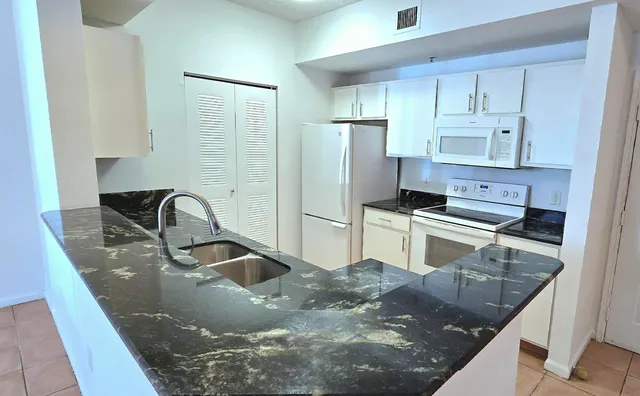 a kitchen with stainless steel appliances granite countertop a sink a stove and a refrigerator with wooden floor