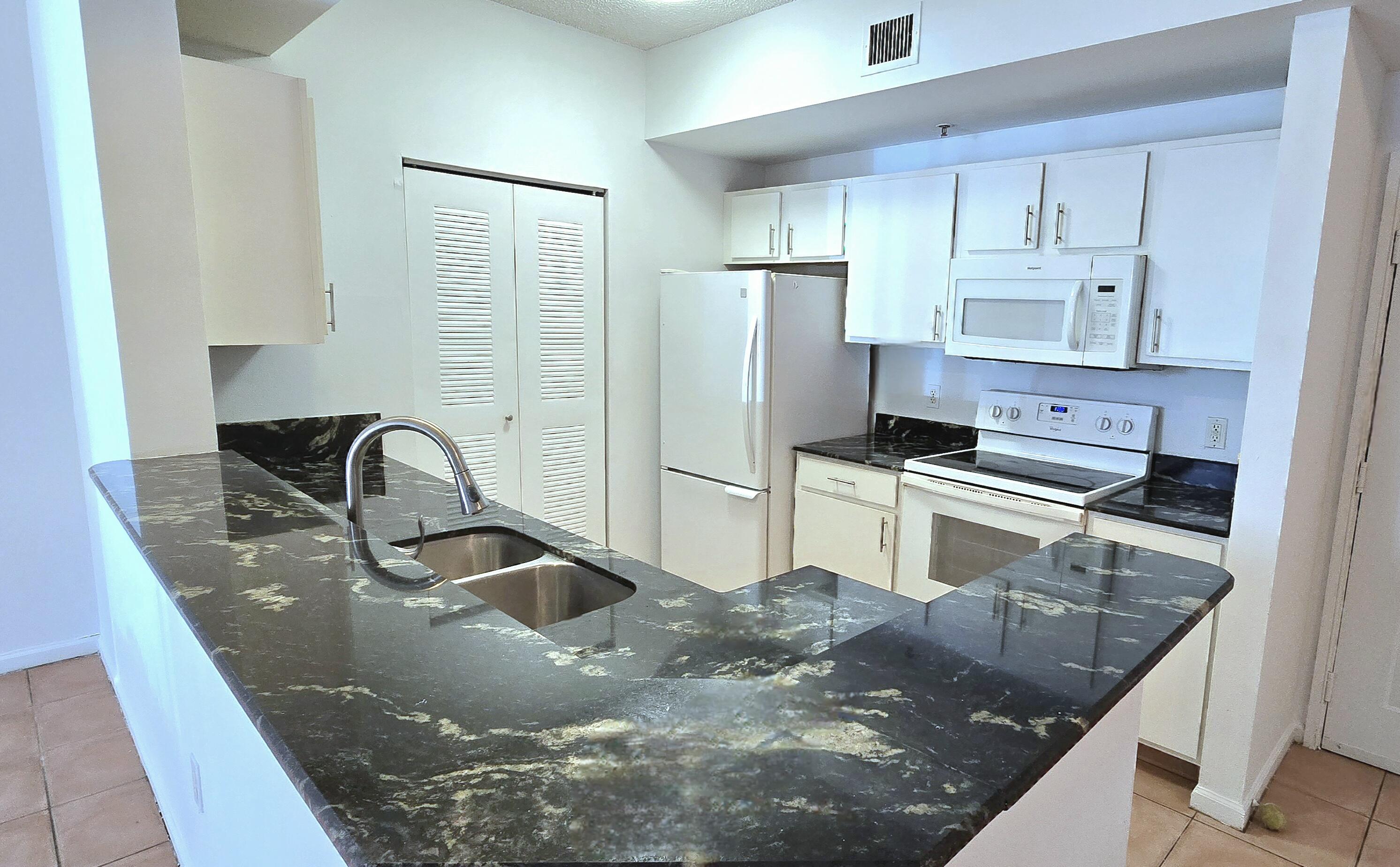 a kitchen with stainless steel appliances granite countertop a sink a stove and a refrigerator with wooden floor