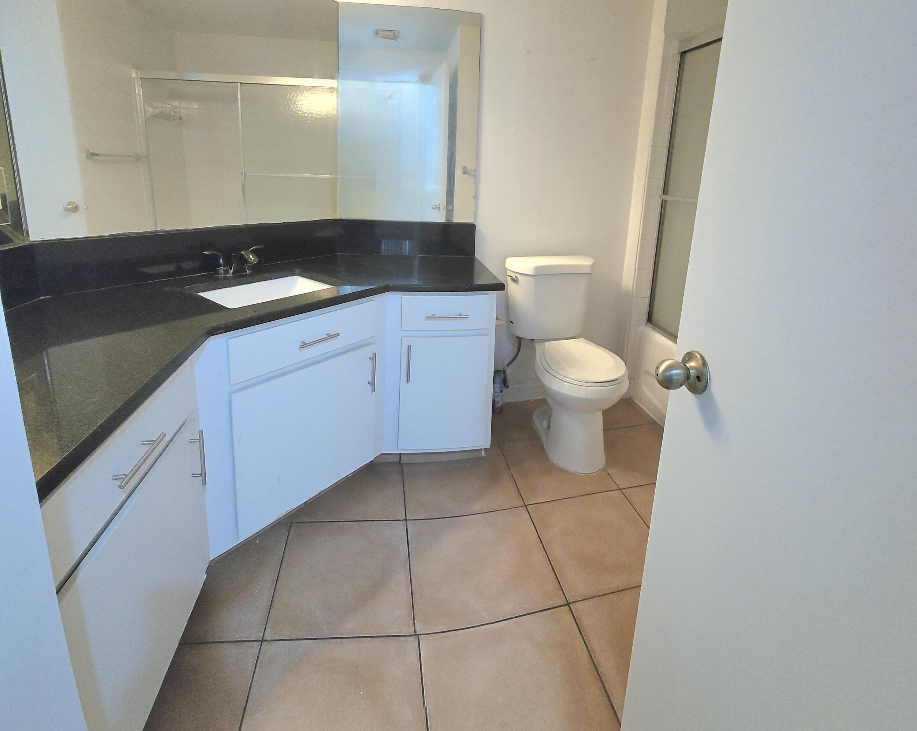 1000 Scotia Drive, Unit 106 Hypoluxo, FL 33462 - Photo 11 of 28 a bathroom with a granite countertop sink a toilet and a mirror
