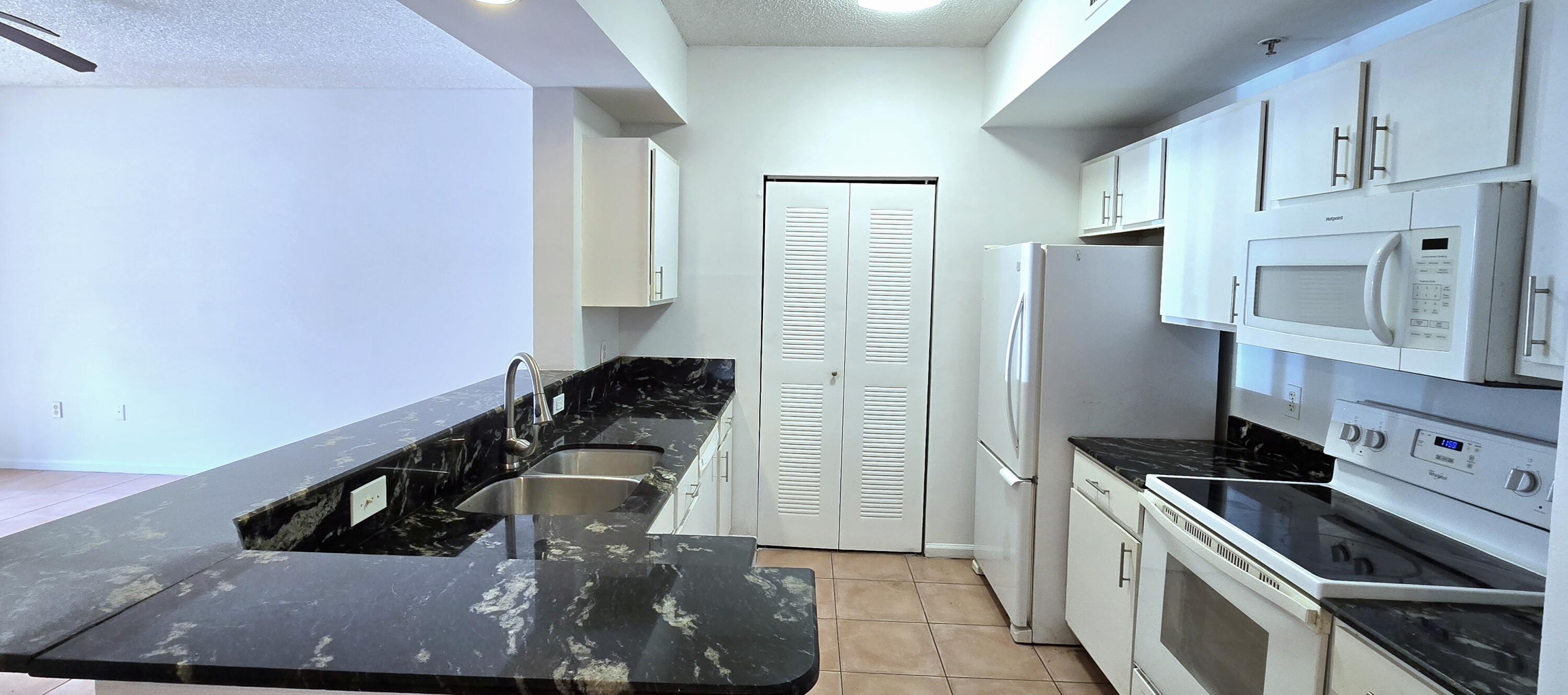 1000 Scotia Drive, Unit 106 Hypoluxo, FL 33462 - Photo 2 of 28 a kitchen with stainless steel appliances granite countertop a sink stove and refrigerator