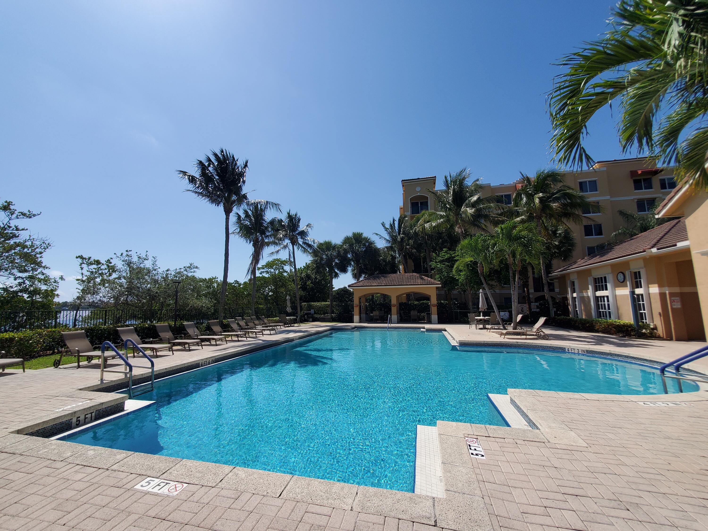 1000 Scotia Drive, Unit 106 Hypoluxo, FL 33462 - Photo 23 of 28 a view of a swimming pool with lawn chairs plants and palm trees