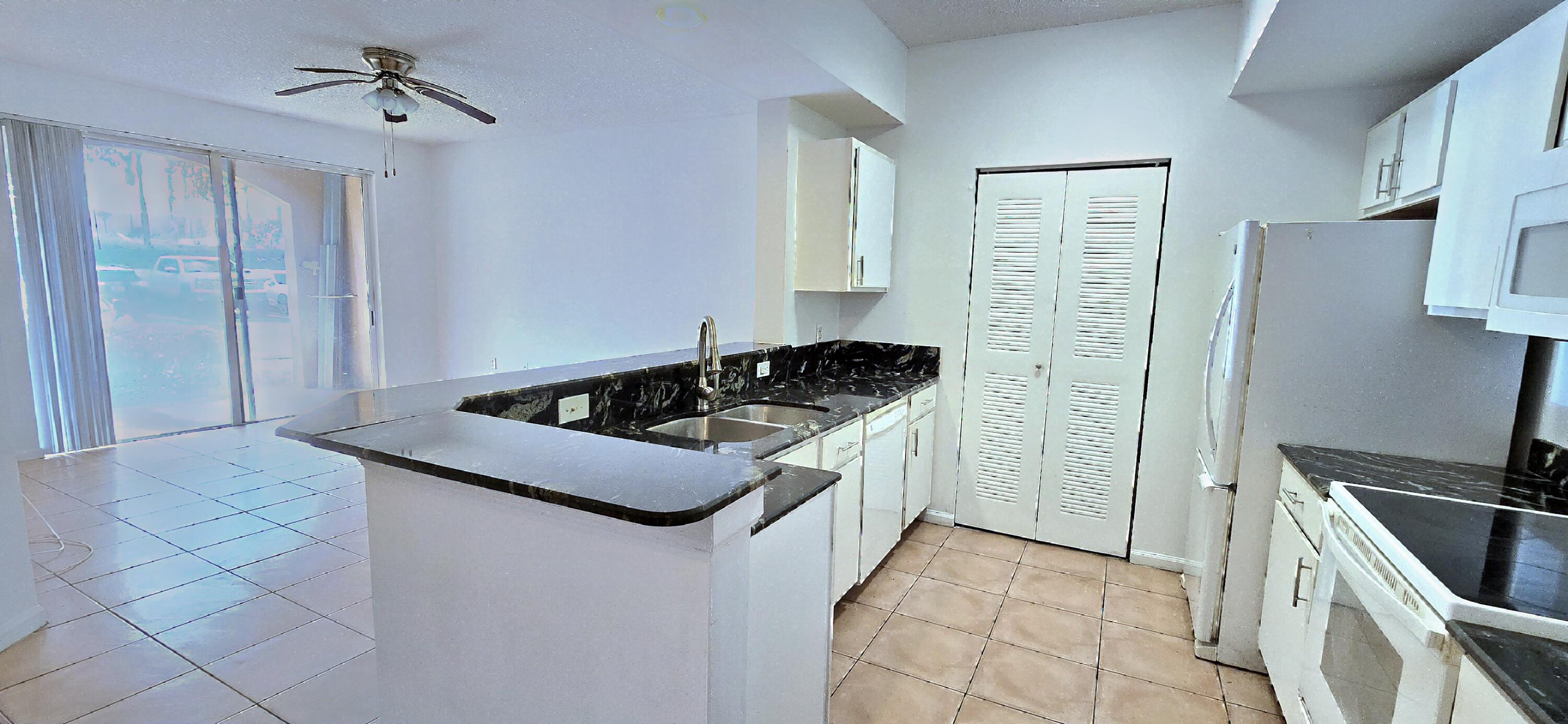1000 Scotia Drive, Unit 106 Hypoluxo, FL 33462 - Photo 3 of 28 a kitchen with stainless steel appliances granite countertop a sink stove and refrigerator