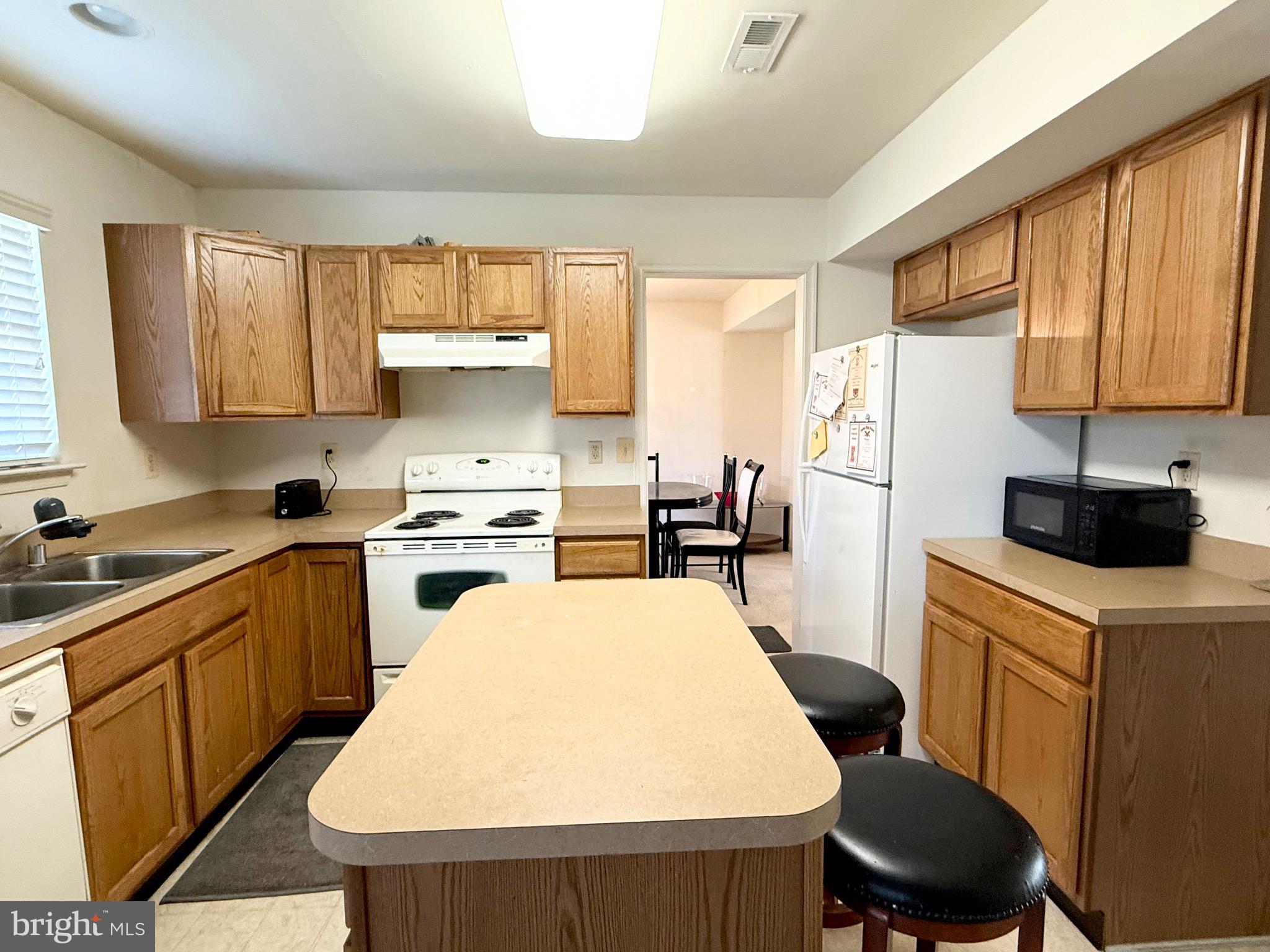 111 Martin Drive Hurlock, MD 21643 - Photo 11 of 27 a kitchen with a refrigerator a stove a sink dishwasher and white cabinets with wooden floor