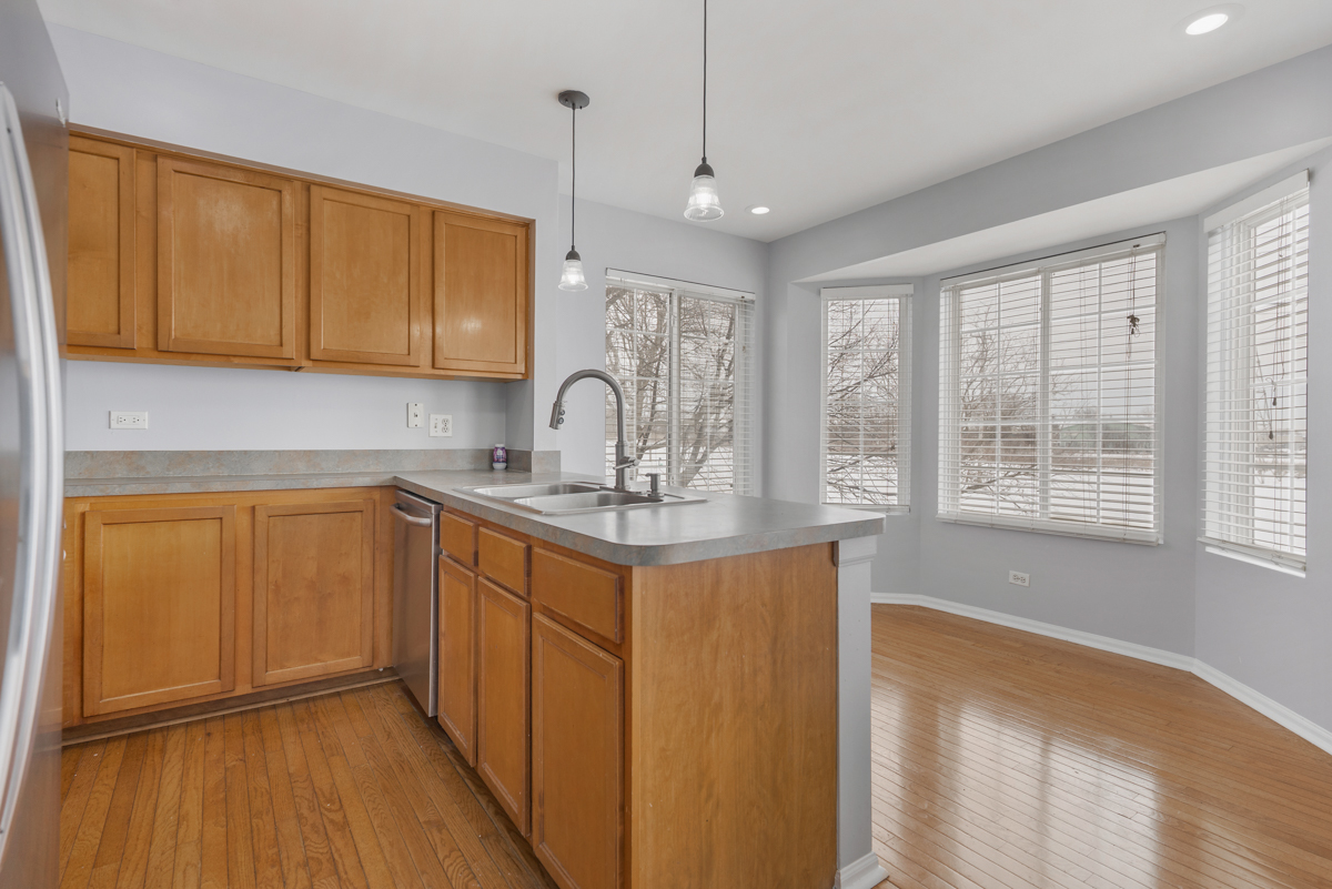 3185 Ketch Court Aurora, IL 60503 - Photo 10 of 25 a kitchen with stainless steel appliances granite countertop a sink a stove cabinets and wooden floor