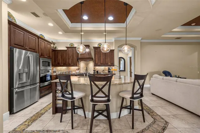 a kitchen with stainless steel appliances kitchen island granite countertop a dining table chairs and granite counter tops