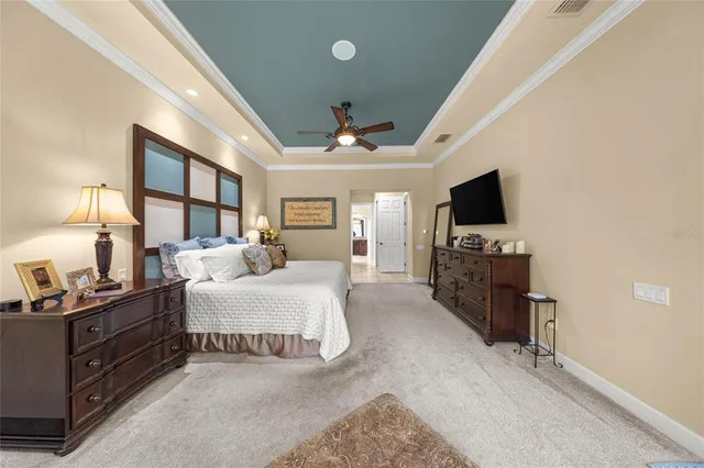 a spacious bedroom with a bed flat screen tv and a chandelier