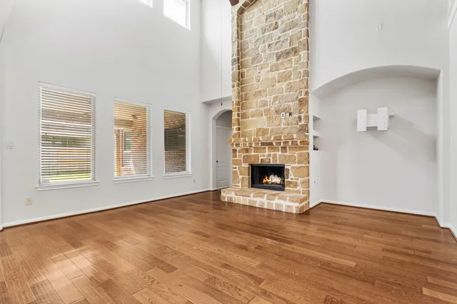 a view of an empty room with wooden floor and a fireplace