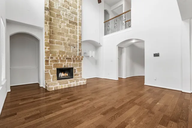 a view of an empty room with wooden floor and a fireplace