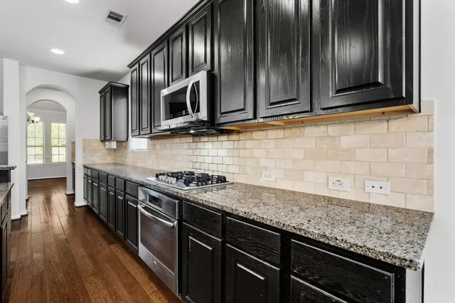 a kitchen with stainless steel appliances granite countertop wooden cabinets stove top oven and sink