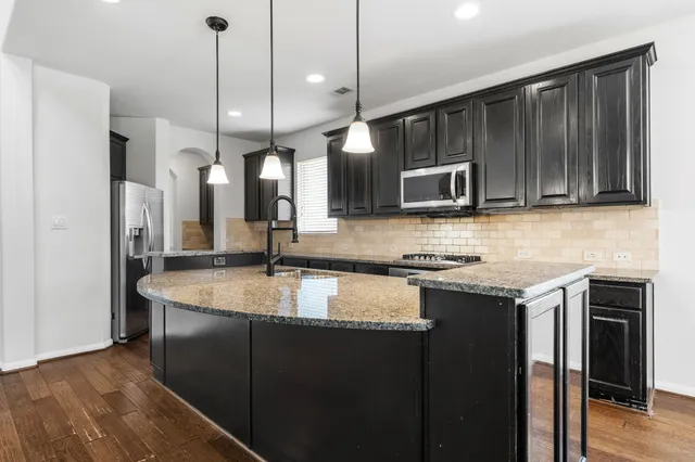 a kitchen with stainless steel appliances granite countertop a sink a stove and a refrigerator