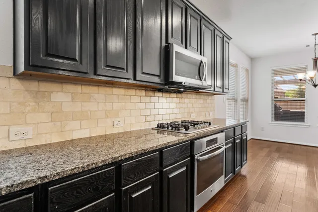 a kitchen with granite countertop cabinets stainless steel appliances and wooden floor