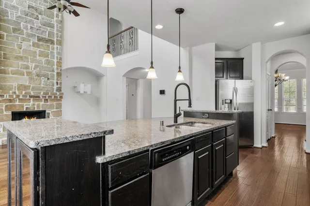 a kitchen with granite countertop a sink a counter space appliances and cabinets