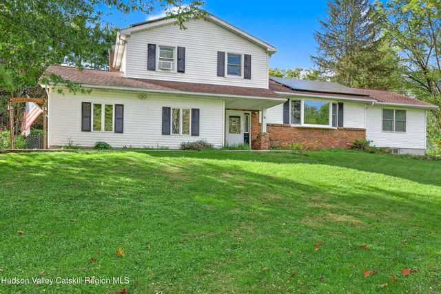 a front view of a house with a garden and trees