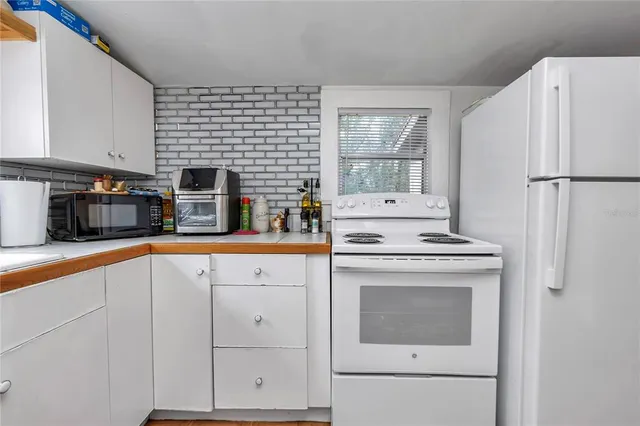 a kitchen with stainless steel appliances granite countertop a refrigerator a stove a sink a dining table and chairs