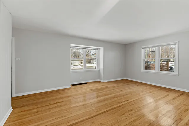a view of an empty room with window and wooden floor
