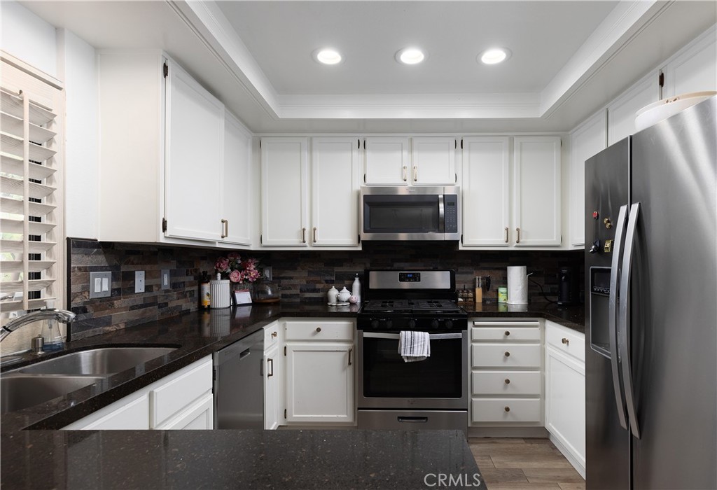 9 Flores Irvine, CA 92612 - Photo 16 of 38 a kitchen with white cabinets and black appliances