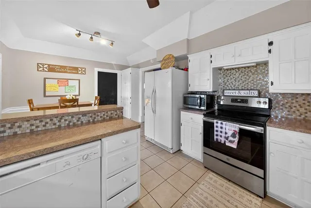 a kitchen with granite countertop a refrigerator a stove a sink and dishwasher